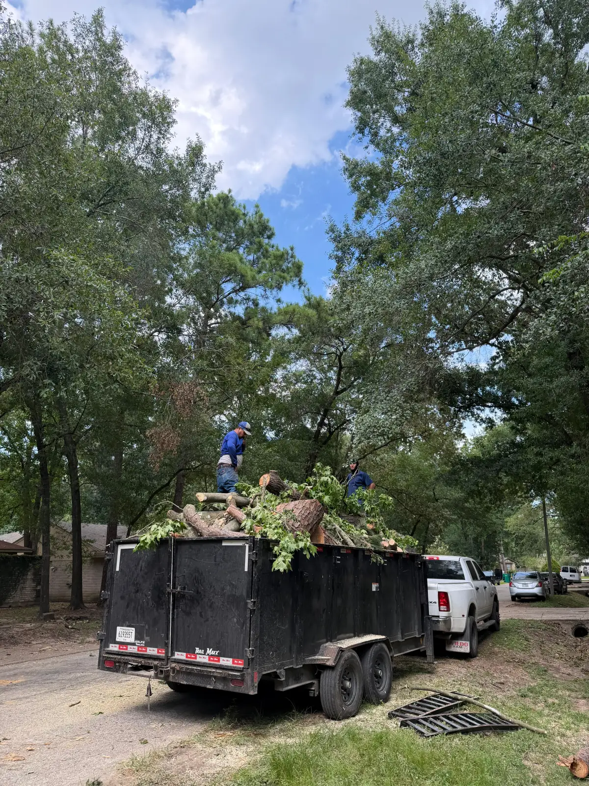 Blossom Exteriors crew loading tree logs and brush into a dump trailer for hauling