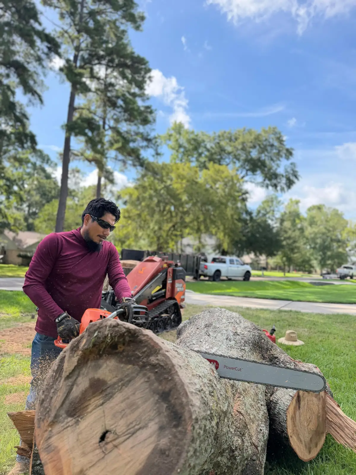 Blossom Exteriors crew member cutting a felled tree trunk with a chainsaw